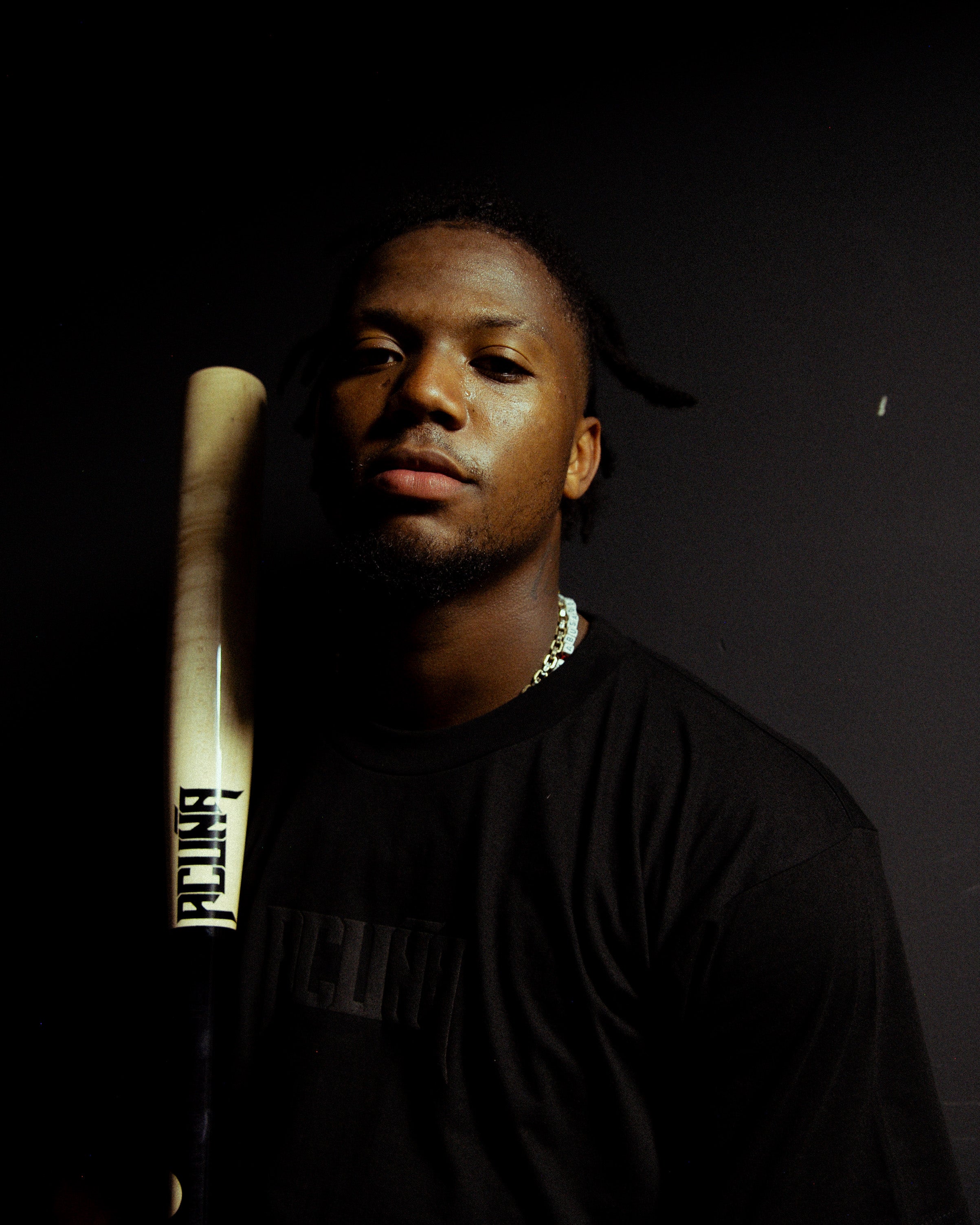 Ronald Acuña wearing a black tee shirt and holding a baseball bat with the "Acuña" logo on it